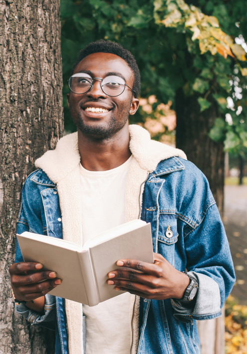 Man Leaning Against Tree While Reading Book